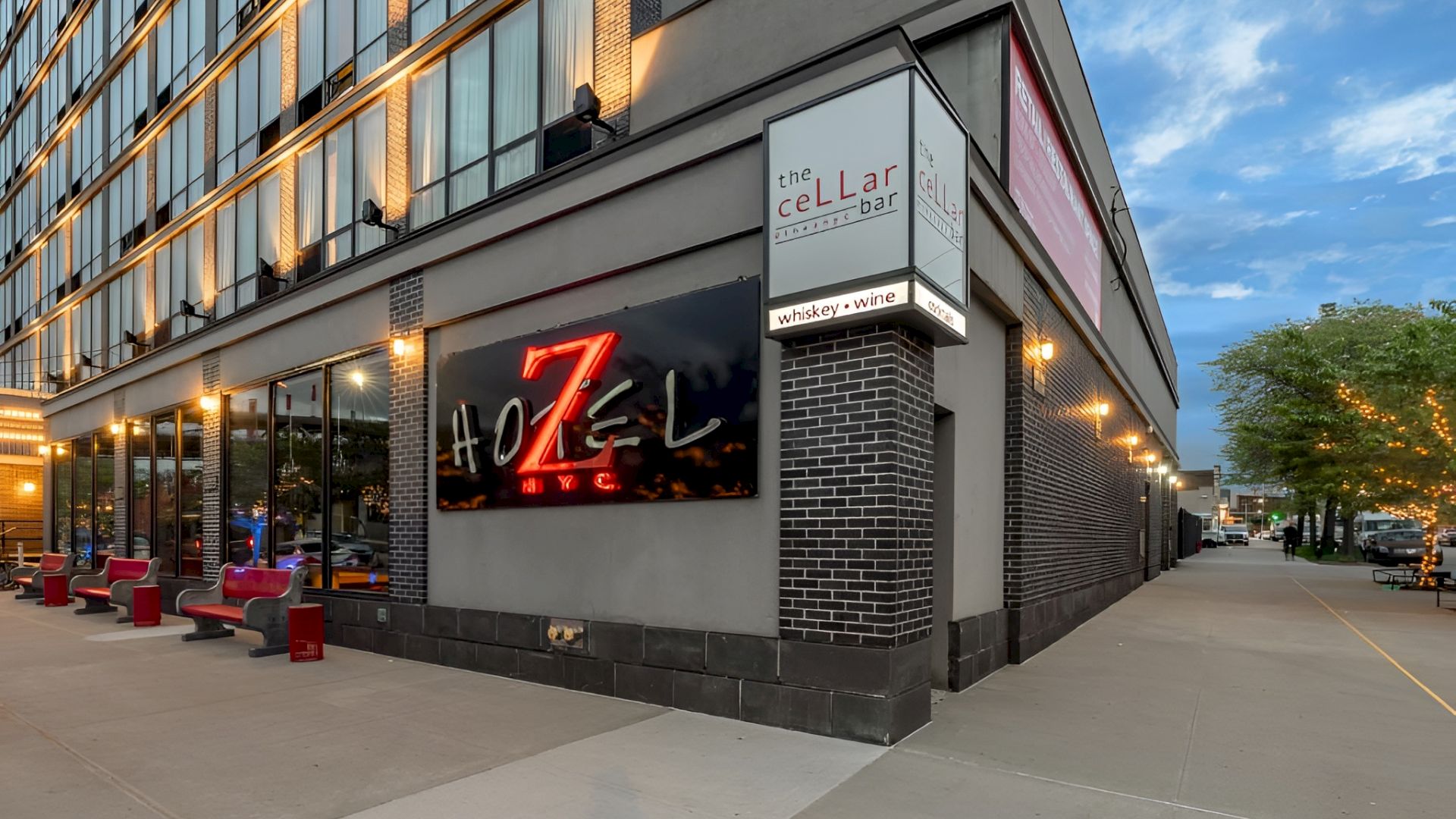 A modern street-front bar/restaurant with outdoor seating along a city sidewalk. 140 characters, ending with a period.
