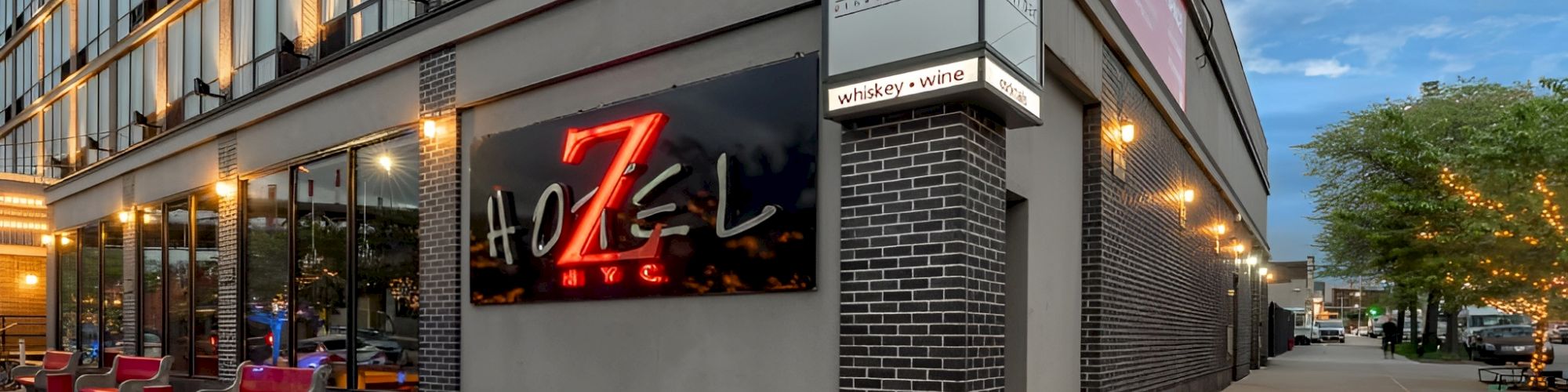 A modern street-front bar/restaurant with outdoor seating along a city sidewalk. 140 characters, ending with a period.
