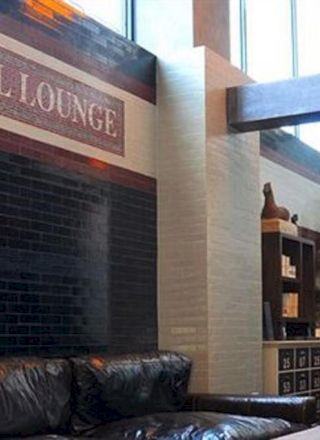 A stylish hotel lobby with a black tiled wall, leather couches, a sign reading “Z HOTEL LOUNGE,” a clock, shelves, and modern decor.